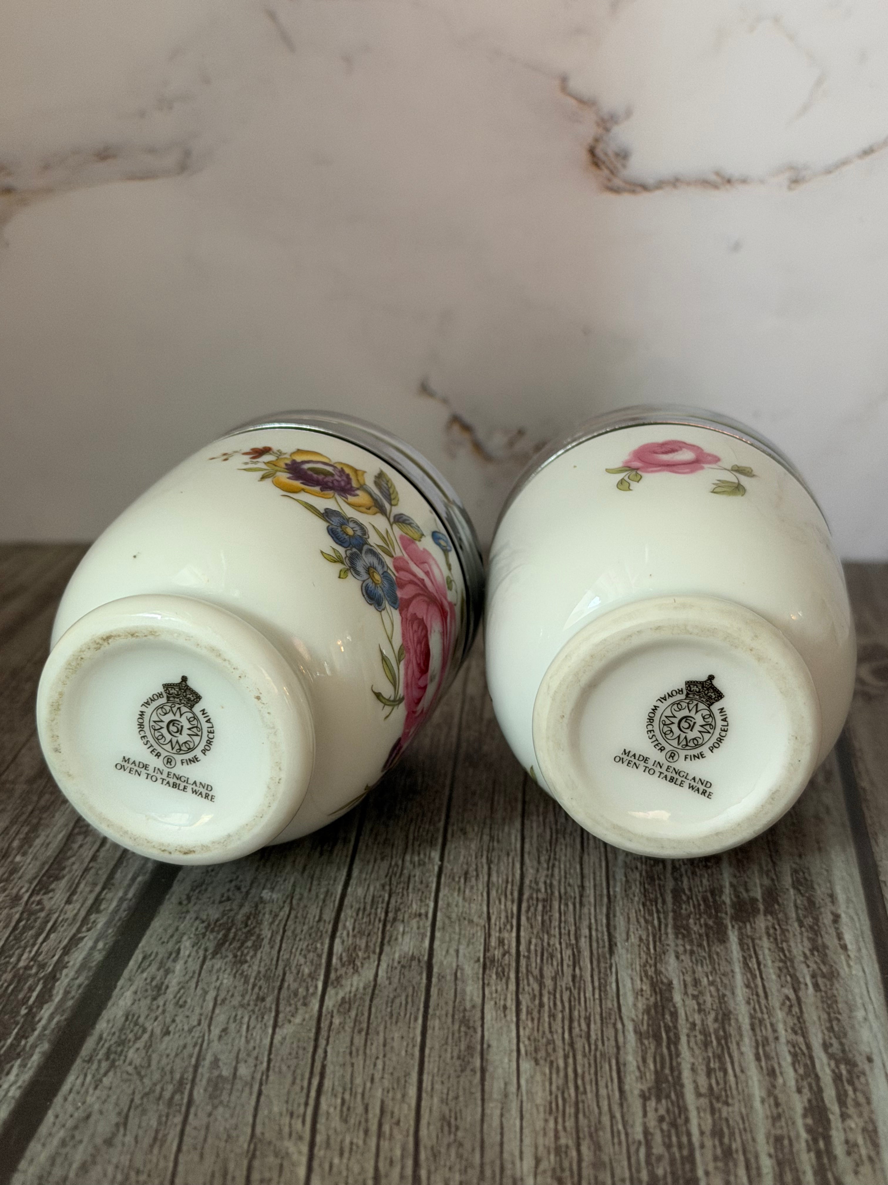 Two ceramic jars with floral designs on a wooden surface.