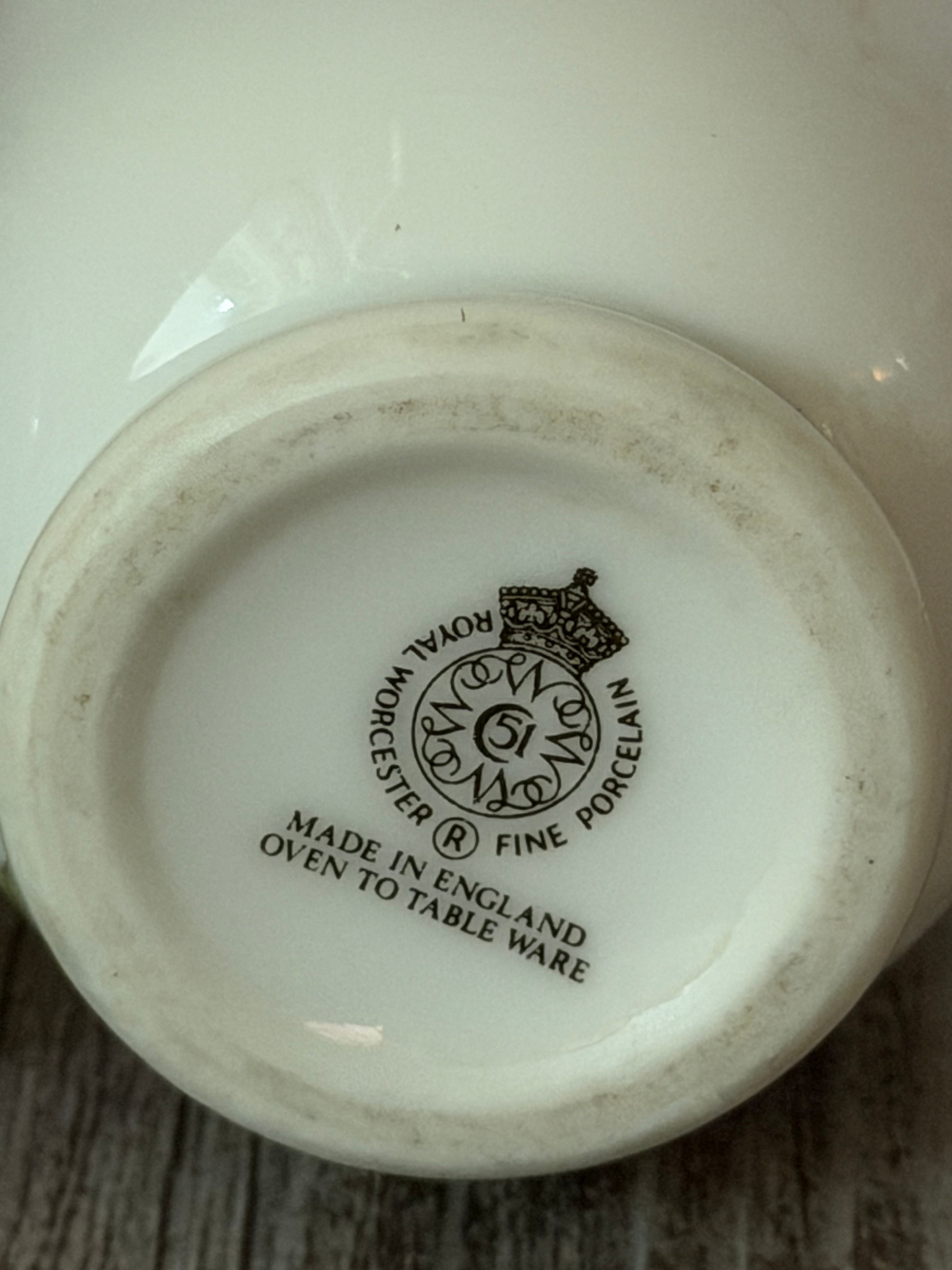 Base of a white ceramic item with black text and logo on a wooden surface