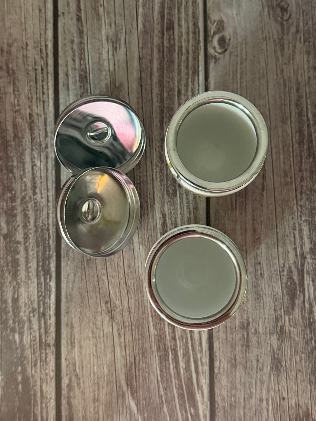 Four metallic bottle caps on a wooden surface