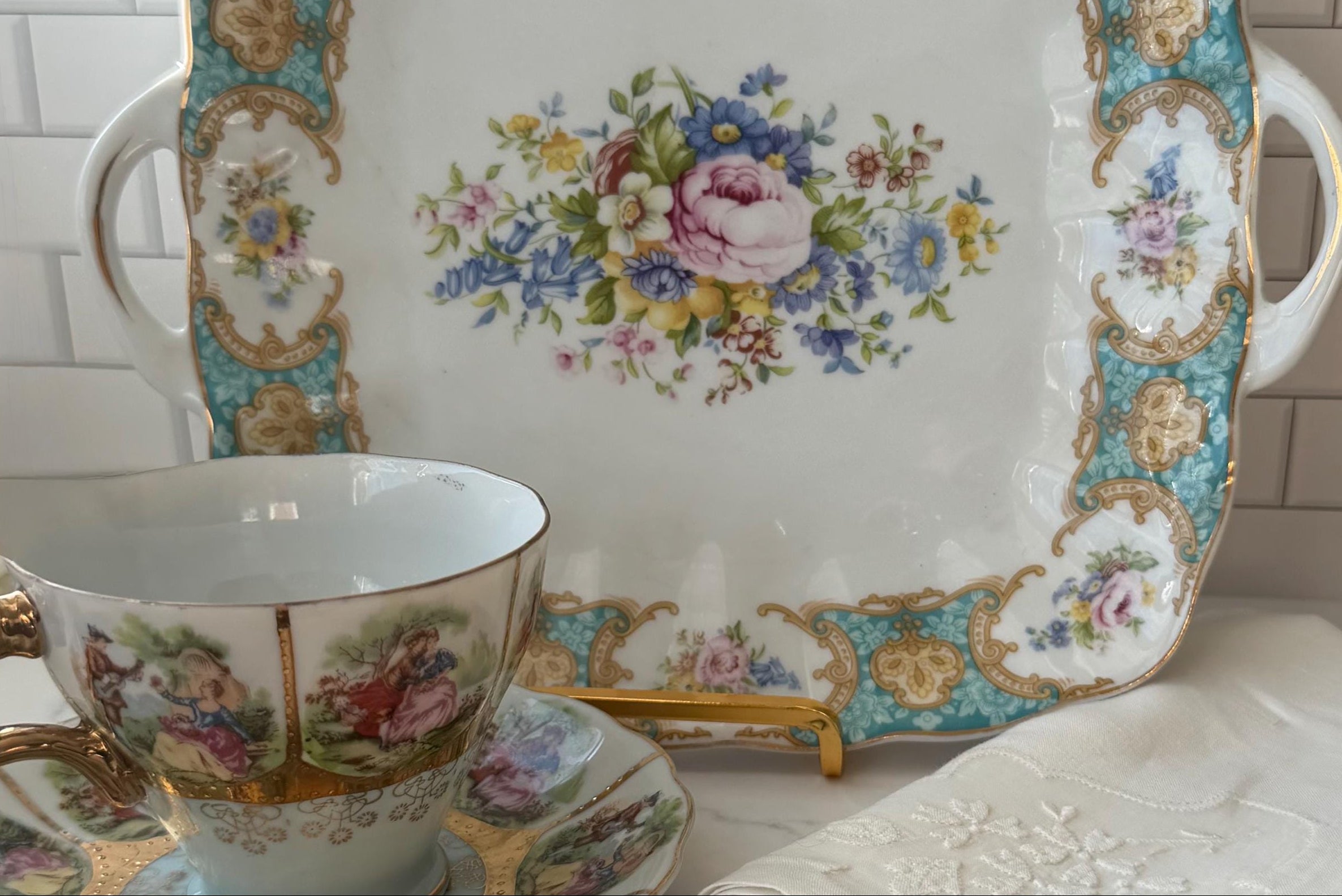Vintage-style teacup, saucer, and plate with floral patterns on a white surface.